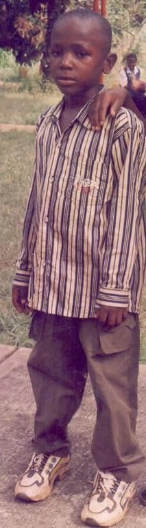 Ugochukwu as a young boy, standing outdoors.